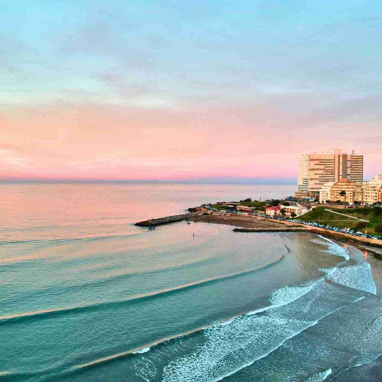 Aerial view of a Buenos Aires beach at sunset with pink skies and crashing waves | Top Flight Deals